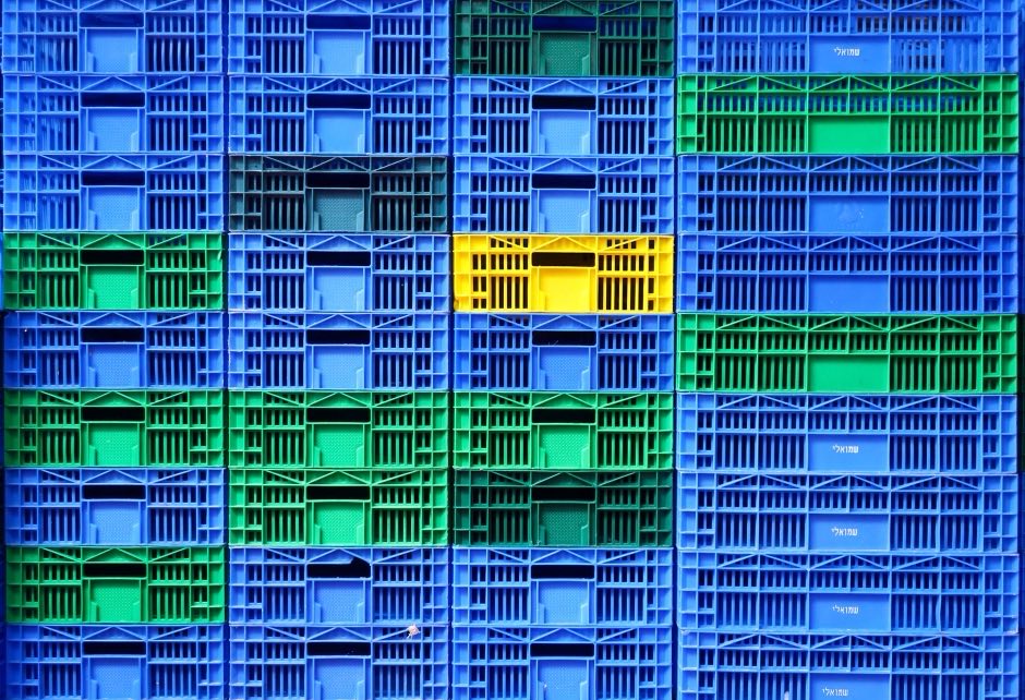 Стена из штабелированных пластиковых ящиков — синие, зелёные и один жёлтый: метафора ABC-классификации, где немногие позиции выделяются из общей массы ассортимента